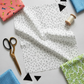 Safari Fun Floating Triangles White/Black by Terry Runyan for Benartex – overhead flat-lay with coordinating Jungle Birds and blue triangle fabrics, gold scissors, thread spool, and cut black and white triangle quilt pieces