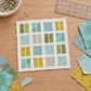 Work-in-progress quilt block with Olive You fabric remnants in leaf green, aqua, blue, and yellow on a sewing table. Quilts shown for inspiration feature the Play a Card Quilt Pattern by Zen Chic — all available at IraRobi Quilts.