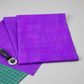 Interwoven Plum quilting cotton displayed in a clean modern sewing workspace with a rotary cutter – vivid purple-violet Interwoven geometric crosshatch fabric by Jason Yenter for In The Beginning Fabrics