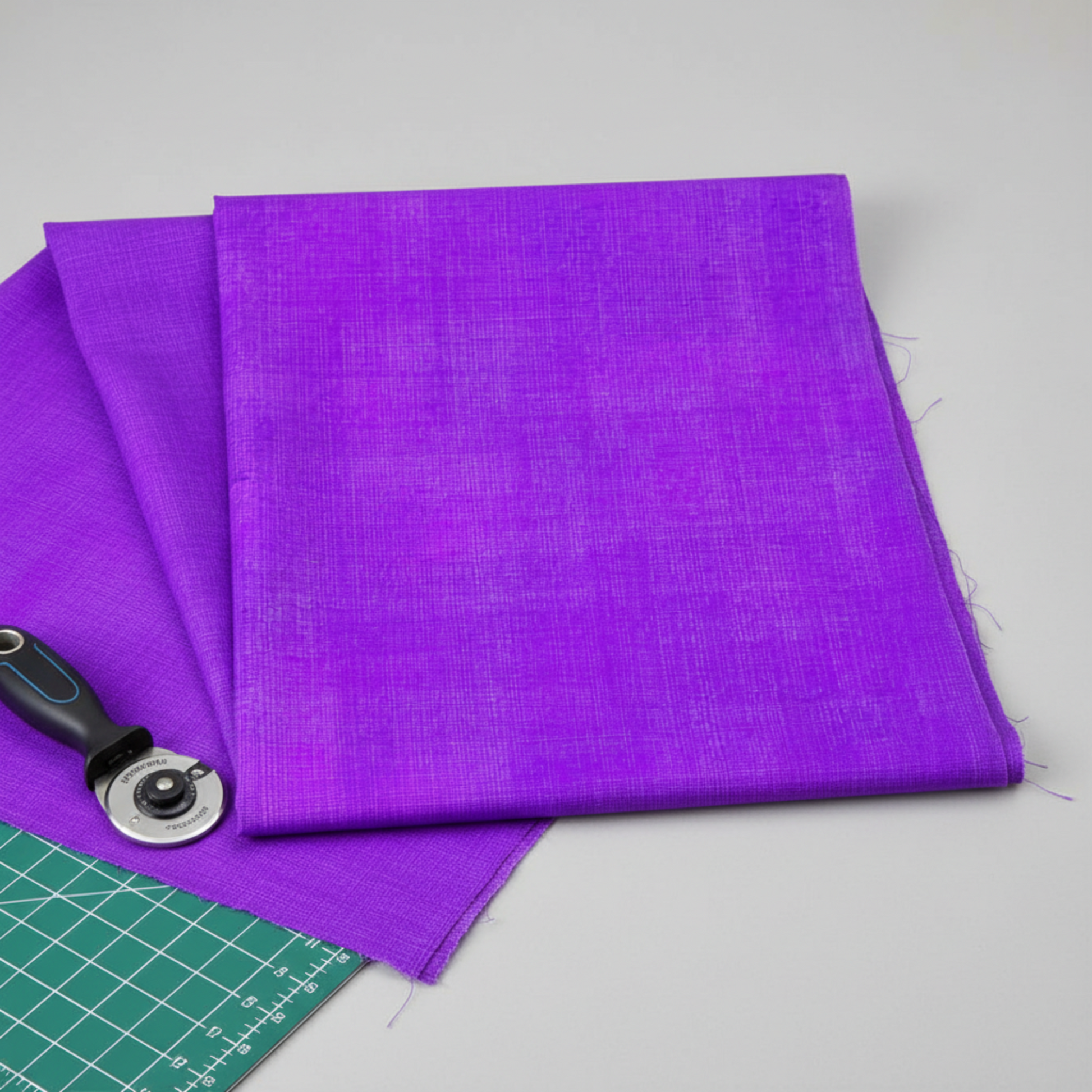 Interwoven Plum quilting cotton displayed in a clean modern sewing workspace with a rotary cutter – vivid purple-violet Interwoven geometric crosshatch fabric by Jason Yenter for In The Beginning Fabrics