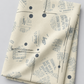 Folded Eggshell News Dropping fabric by Zen Chic for Moda Fabrics on a light gray background, showing its newsprint-style fragments, charcoal dots, and dotted lines.