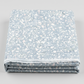 Terrazzo Powdered Pearl Fabric by Riley Blake Designs folded on a light-gray background, showing its pale pebble print and raw cut edge.