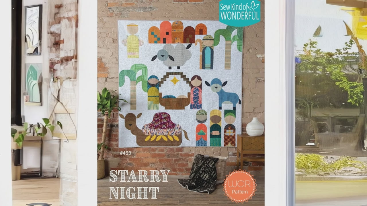 Colorful nativity scene wall quilt in a room with a window.