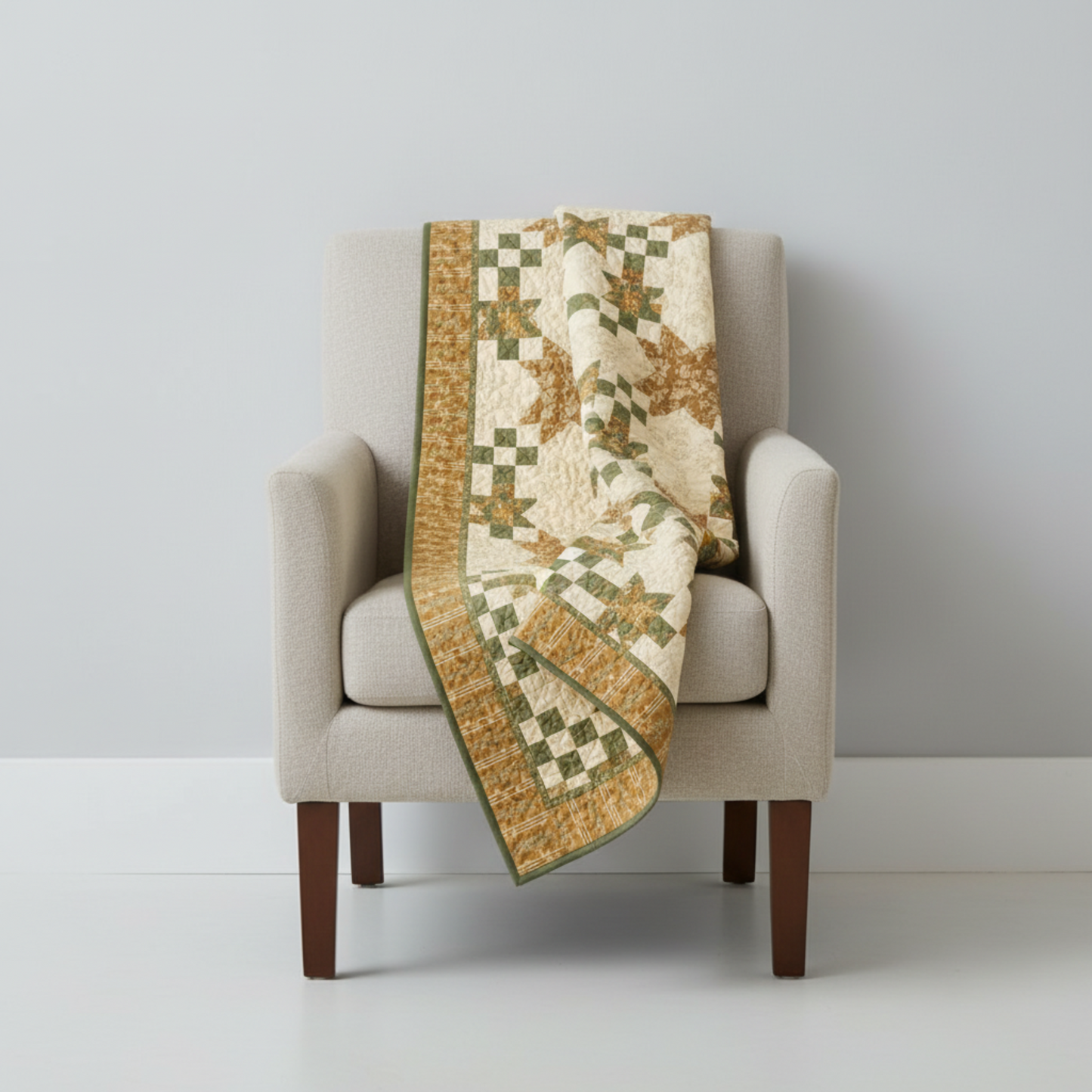 Traditional star and nine-patch quilt draped over a linen armchair — made with Front Porch coordinating fabrics by Dolores Smith for Marcus Fabrics in sage green, cream, and olive-gold