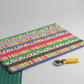 Safari Fun Playful Strip Multi quilting cotton partially folded on a cutting mat with a rotary cutter — multicolor geometric strip print by Terry Runyan for Benartex