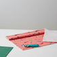 Safari Fun Jungle Birds Sorbet quilting cotton partially folded on a cutting mat with a rotary cutter — coral parrot print by Terry Runyan for Benartex