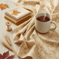 Reflections of Autumn II Twigs 3 Yard Cut quilting cotton by Jason Yenter for In The Beginning Fabrics — loosely draped on a warm white wooden surface with coordinating cream, taupe, and gold fabric swatches, cream thread spool, dried wheat stalks, pressed autumn leaves, and a mug of tea in a soft dreamy sewing room.