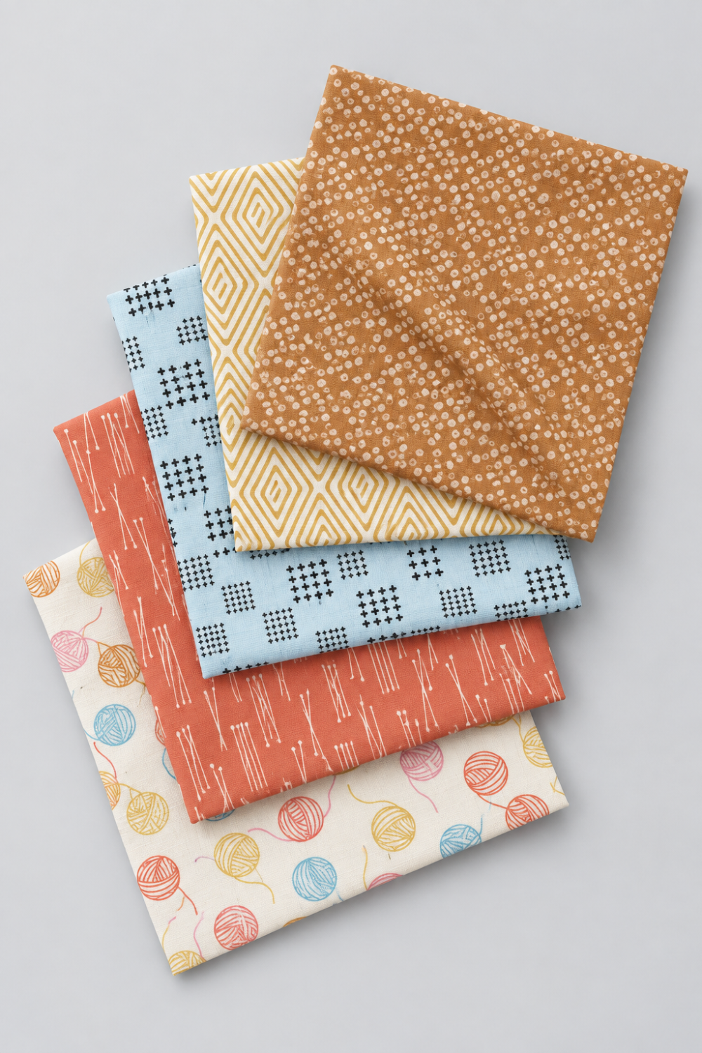 Five Lazy Afternoon fabrics layered in a vertical stack, with Bronze’s pale dotted print on top and coordinating prints beneath.