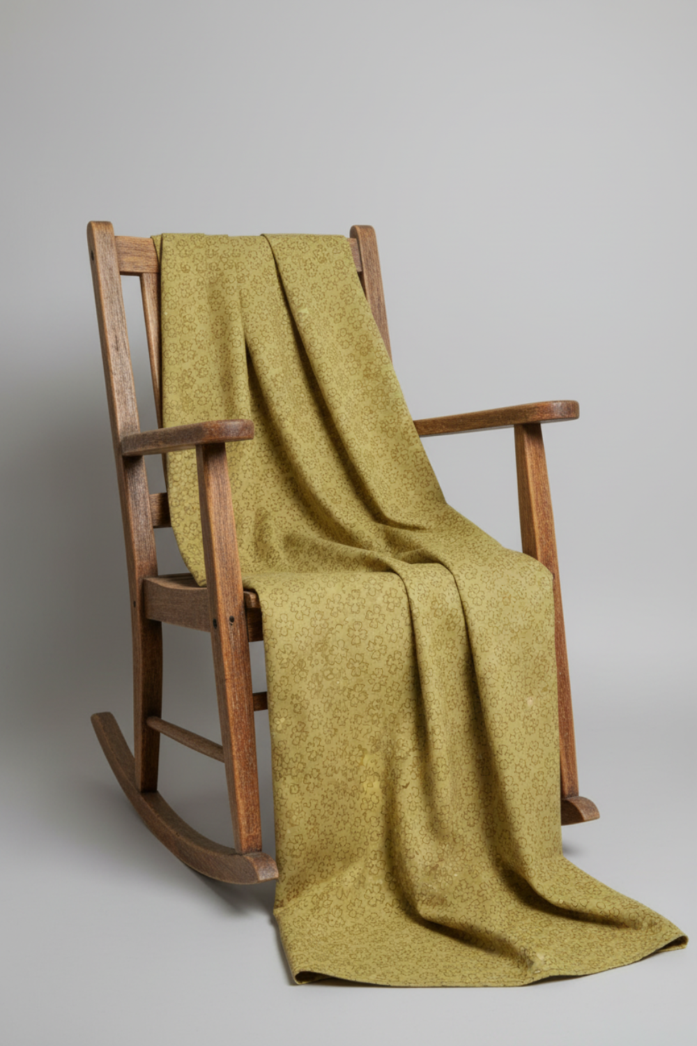 Golden Era by Paula Barnes, Wavy Daisy Green for Marcus Fabrics — sage-olive green quilting cotton with wavy daisy motif draped over a rustic rocking chair, 100% cotton 43–44" wide — IraRobi Quilts