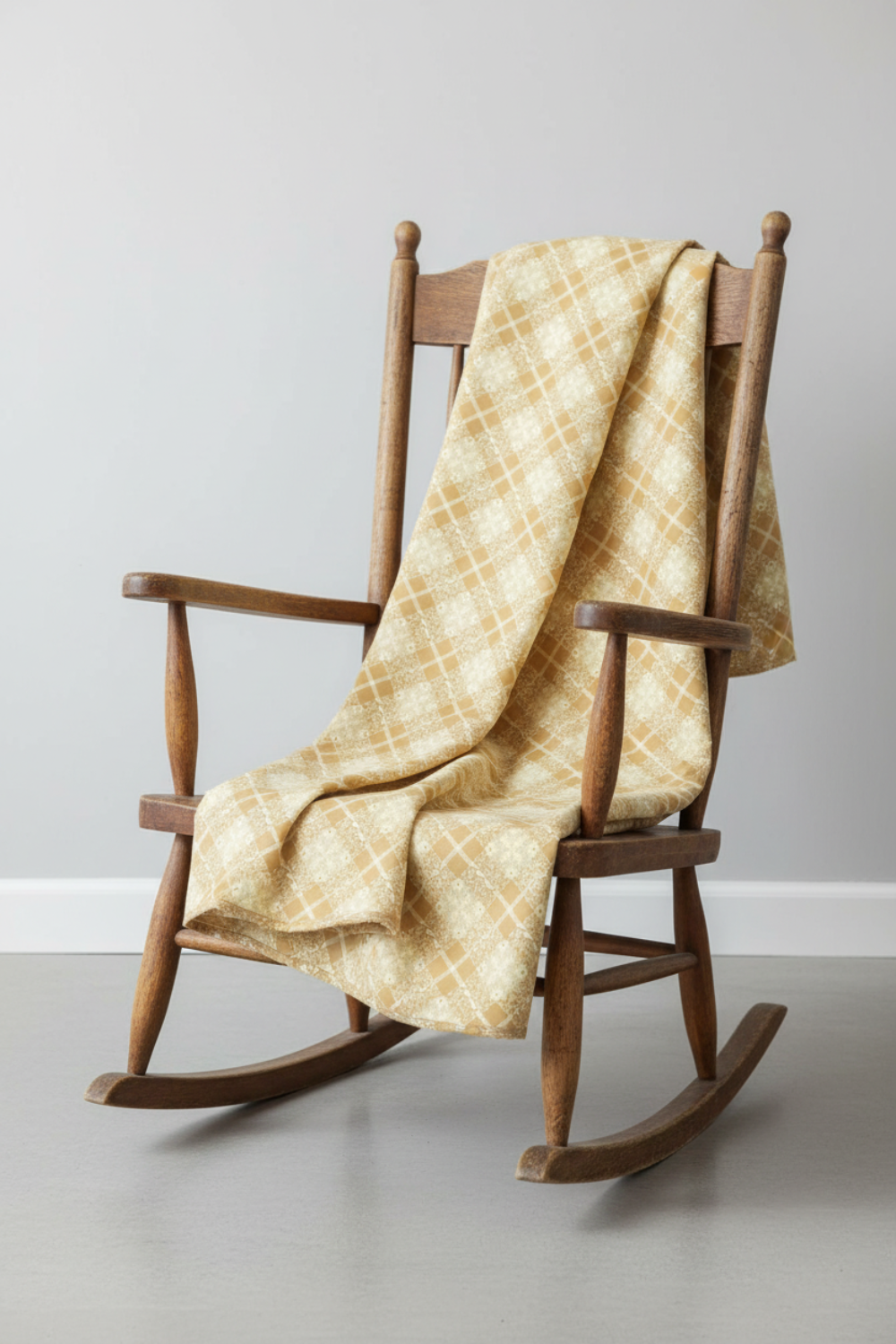 Golden Era by Paula Barnes, Floral Plaid Tan for Marcus Fabrics — warm tan-gold quilting cotton with diagonal lattice and cream floral wreath motifs draped over a rustic rocking chair — IraRobi Quilts