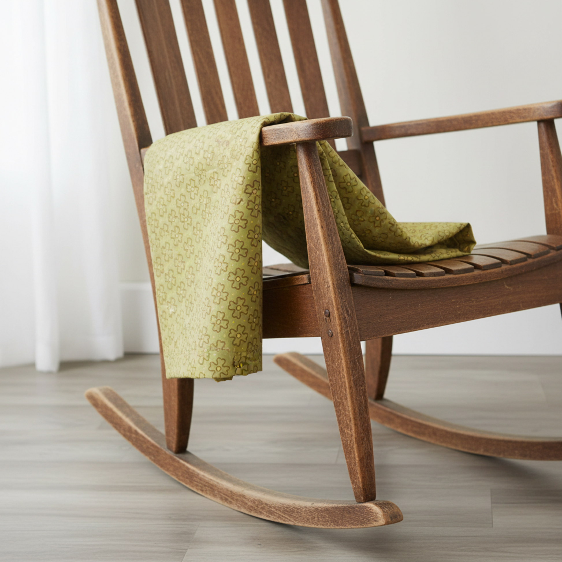 Golden Era Wavy Daisy Green quilting cotton by Paula Barnes for Marcus Fabrics — fabric draped over a rustic wooden rocking chair showing natural drape and sage-olive green wavy daisy print