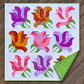 Rose Garden quilt laid on wooden decking with a corner folded back to reveal its green patterned backing and coordinating binding.