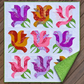 Rose Garden quilt on wooden decking with a corner folded back to reveal its green patterned backing and coordinating binding.