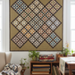 Rudy's Farm Quilt Pattern by Jill Shaulis for Yellow Creek Quilt Designs — 63"×63" scrappy snowflake block quilt displayed in a cozy farmhouse quilting room. Blocks in groups of four set on point in blues, reds, greens, golds, and purples on cream, with dark brown floral sashing and warm tan background. Quilt shown for inspiration. Available at IraRobi Quilts.