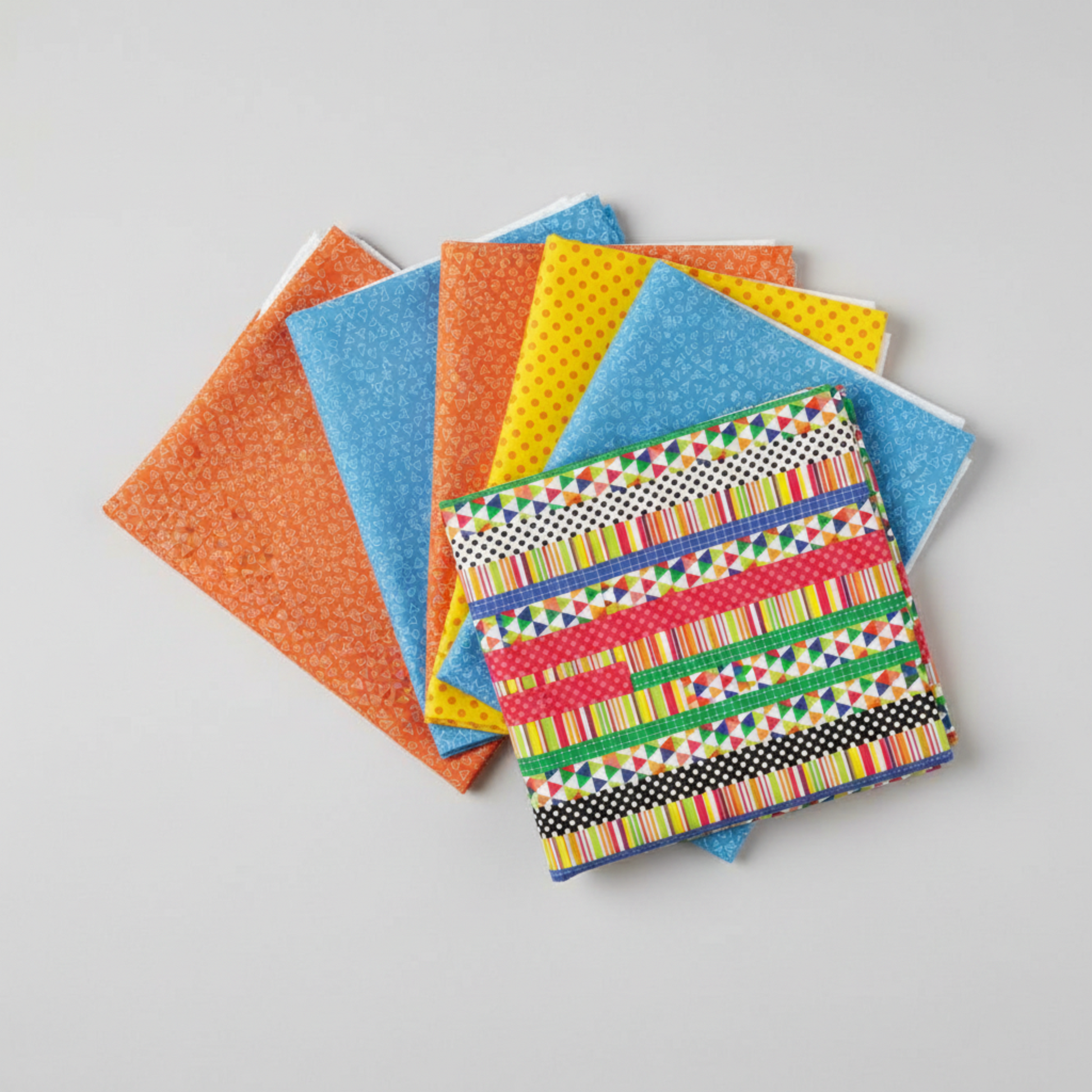 Safari Fun coordinating fat quarter bundle — Playful Strip Multi with orange triangles, blue triangles, and yellow polka dot quilting fabrics fanned on light grey background — IraRobi Quilts