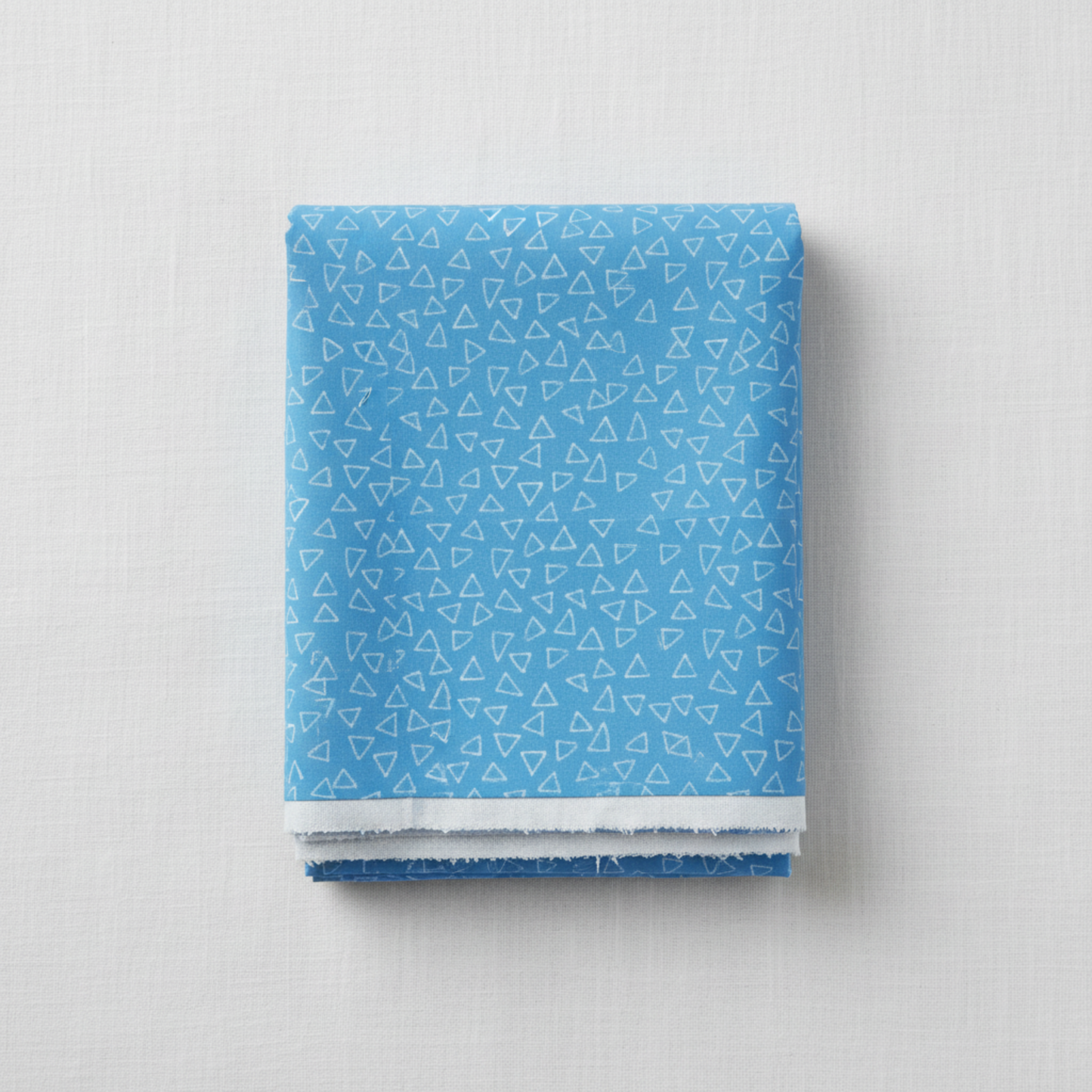 Safari Fun Floating Triangles Blue quilting cotton by Terry Runyan for Benartex — neatly folded fabric bolt showing cornflower blue with scattered white hand-drawn triangle outlines, 100% cotton, 43–44" wide.
