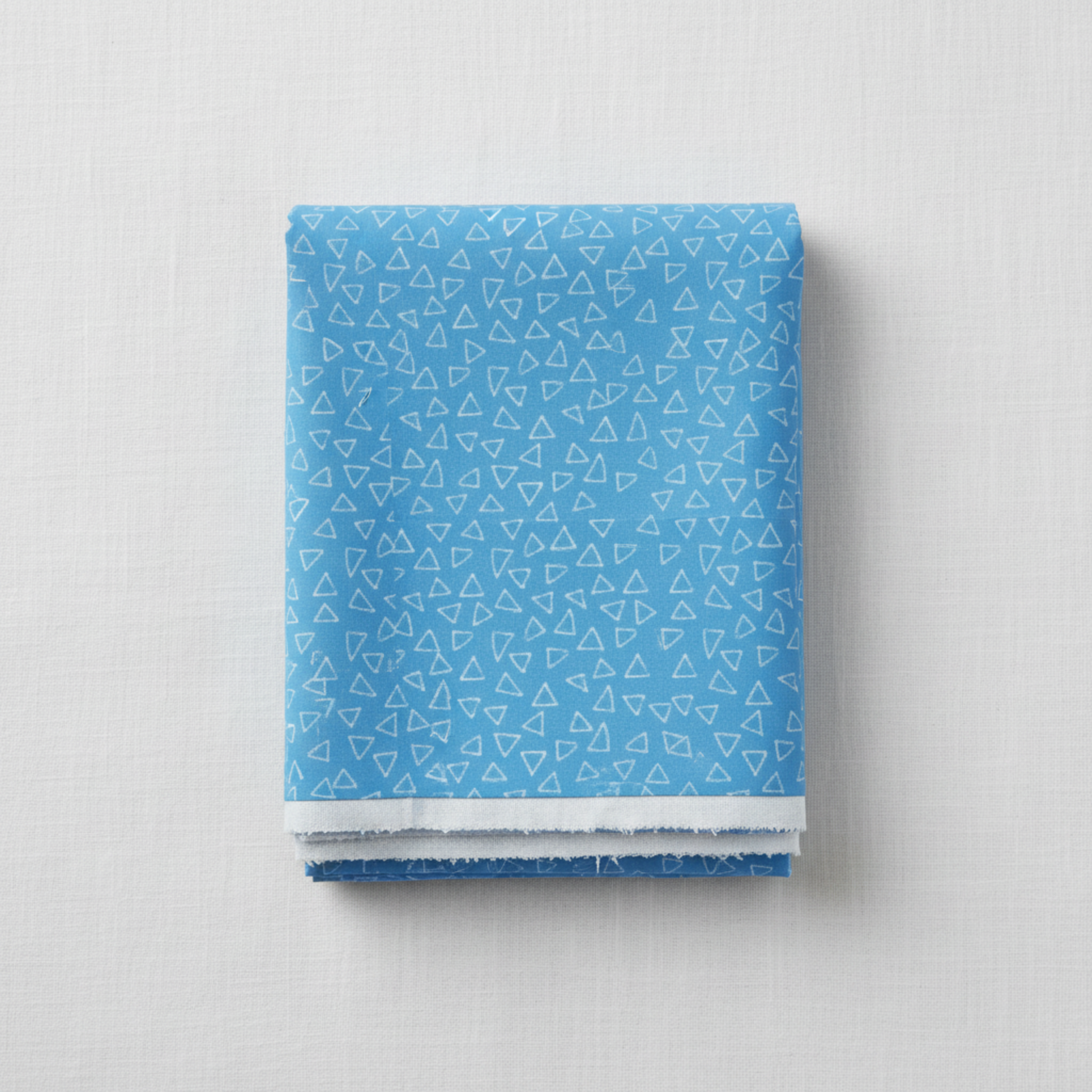 Safari Fun Floating Triangles Blue quilting cotton by Terry Runyan for Benartex — neatly folded fabric bolt showing cornflower blue with scattered white hand-drawn triangle outlines, 100% cotton, 43–44" wide.