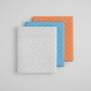 Safari Fun Floating Triangles quilting fabric in three colorways – white with black outlines, cornflower blue with white outlines, and orange with white outlines, folded and stacked on light grey background