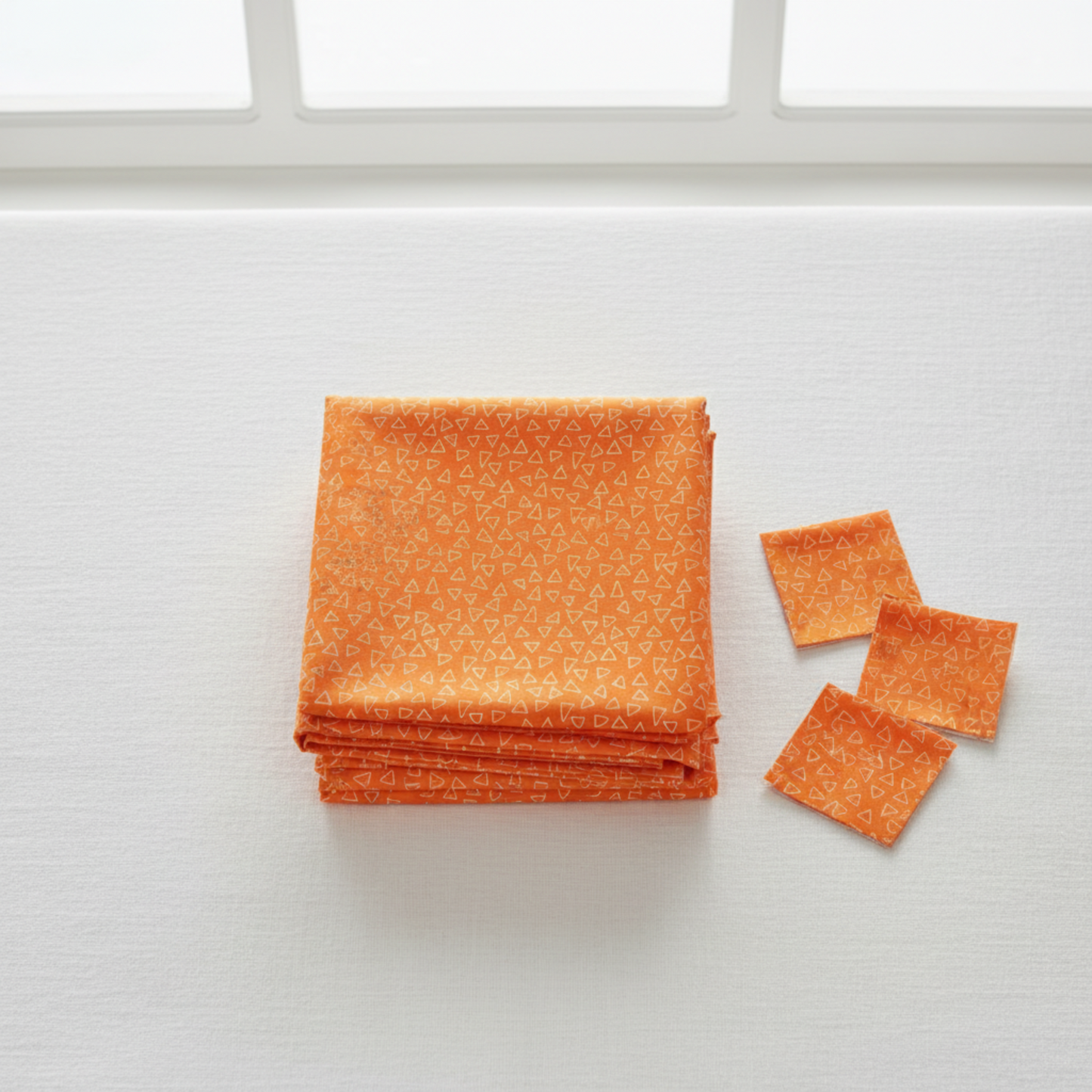 Safari Fun Floating Triangles Orange quilting cotton by Terry Runyan for Benartex — folded fabric stack showing vibrant orange with scattered white hand-drawn triangle outlines, 100% cotton. Quilt blocks shown for inspiration. Coordinating fabrics and quilt patterns are available at IraRobi Quilts.