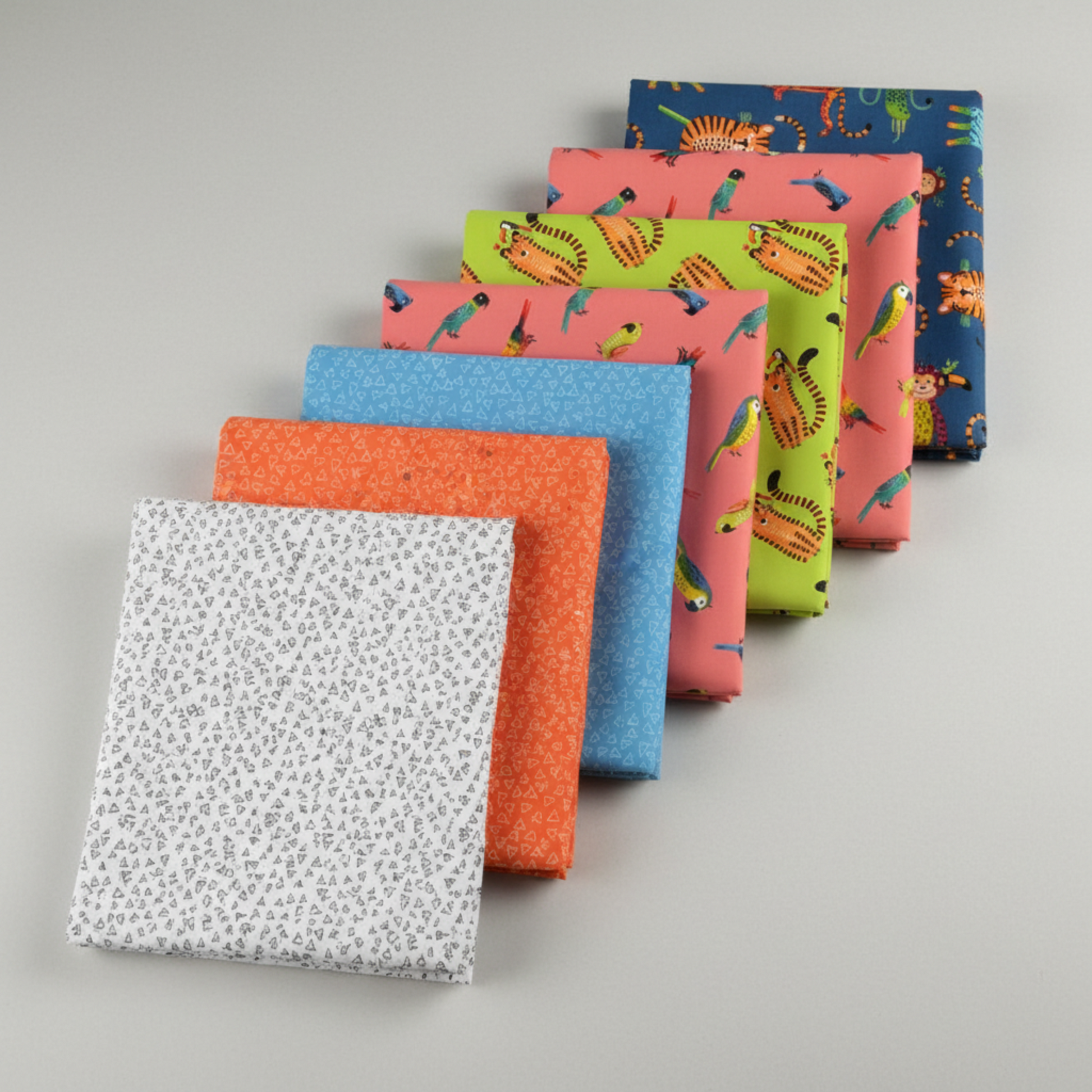 Safari Fun complete collection by Terry Runyan for Benartex – seven coordinating quilting fabrics fanned in a stack, Floating Triangles White/Black as hero with orange, blue, coral, lime, pink, and navy coordinates