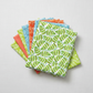 Safari Fun Jungle Leaves White by Terry Runyan for Benartex shown in a coordinating fabric stack with prints in coral sorbet, orange, cornflower blue, and lime green. Quilt blocks shown for inspiration. Coordinating fabrics and quilt patterns are available at IraRobi Quilts.