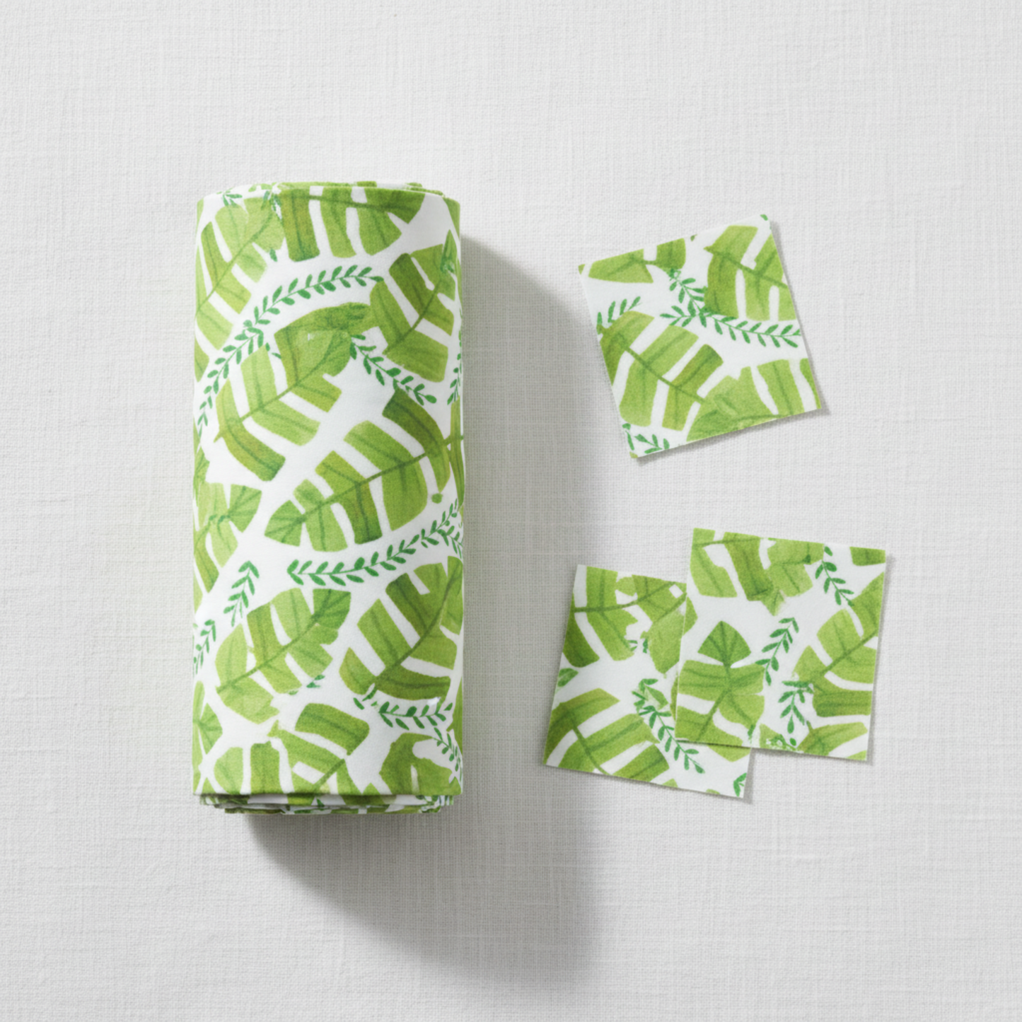 Safari Fun Jungle Leaves White quilting cotton by Terry Runyan for Benartex — folded fabric bolt showing watercolor tropical banana leaves and fern sprigs in fresh greens on crisp white, 100% cotton. Quilt blocks shown for inspiration. Coordinating fabrics and quilt patterns are available at IraRobi Quilts.