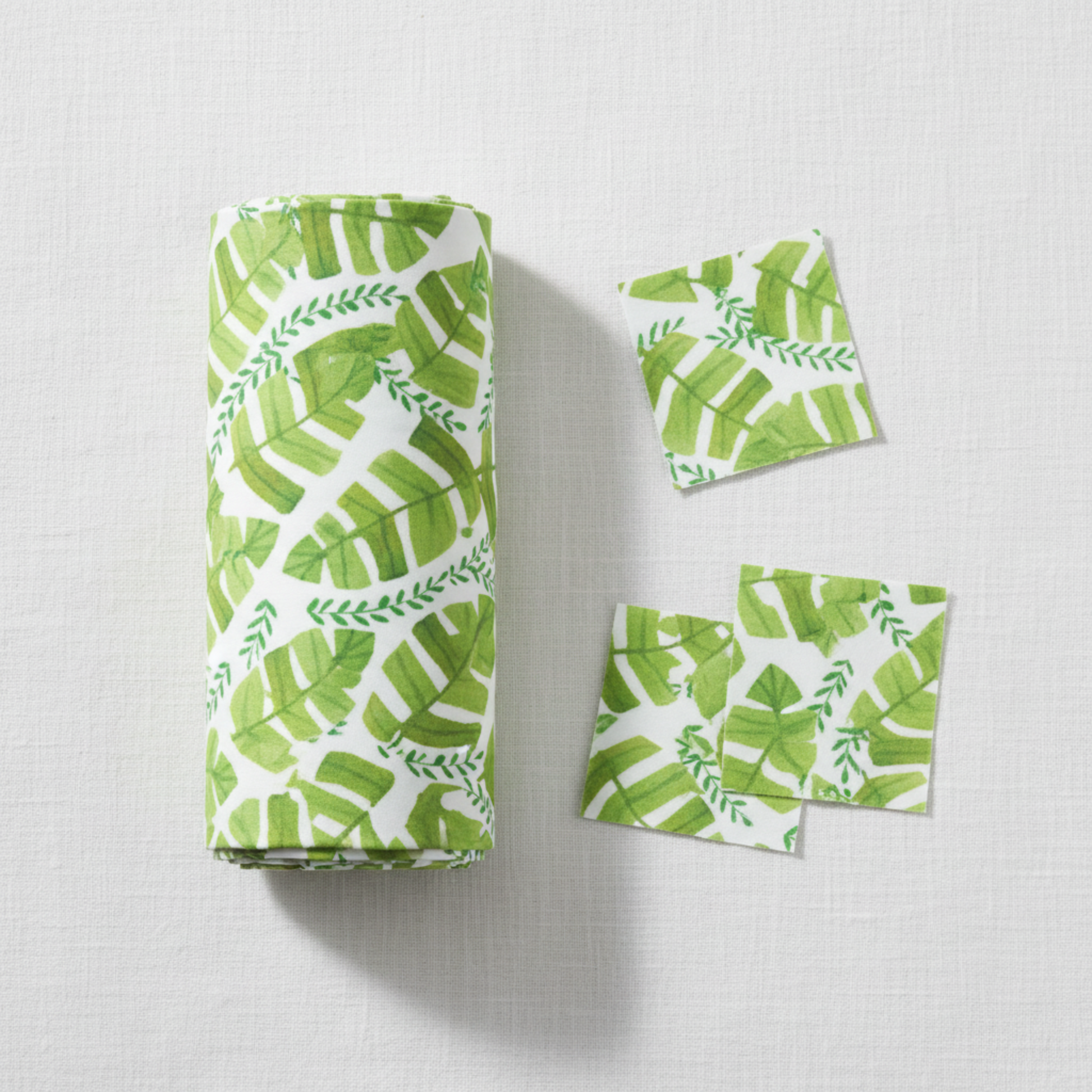 Safari Fun Jungle Leaves White quilting cotton by Terry Runyan for Benartex — folded fabric bolt showing watercolor tropical banana leaves and fern sprigs in fresh greens on crisp white, 100% cotton. Quilt blocks shown for inspiration. Coordinating fabrics and quilt patterns are available at IraRobi Quilts.