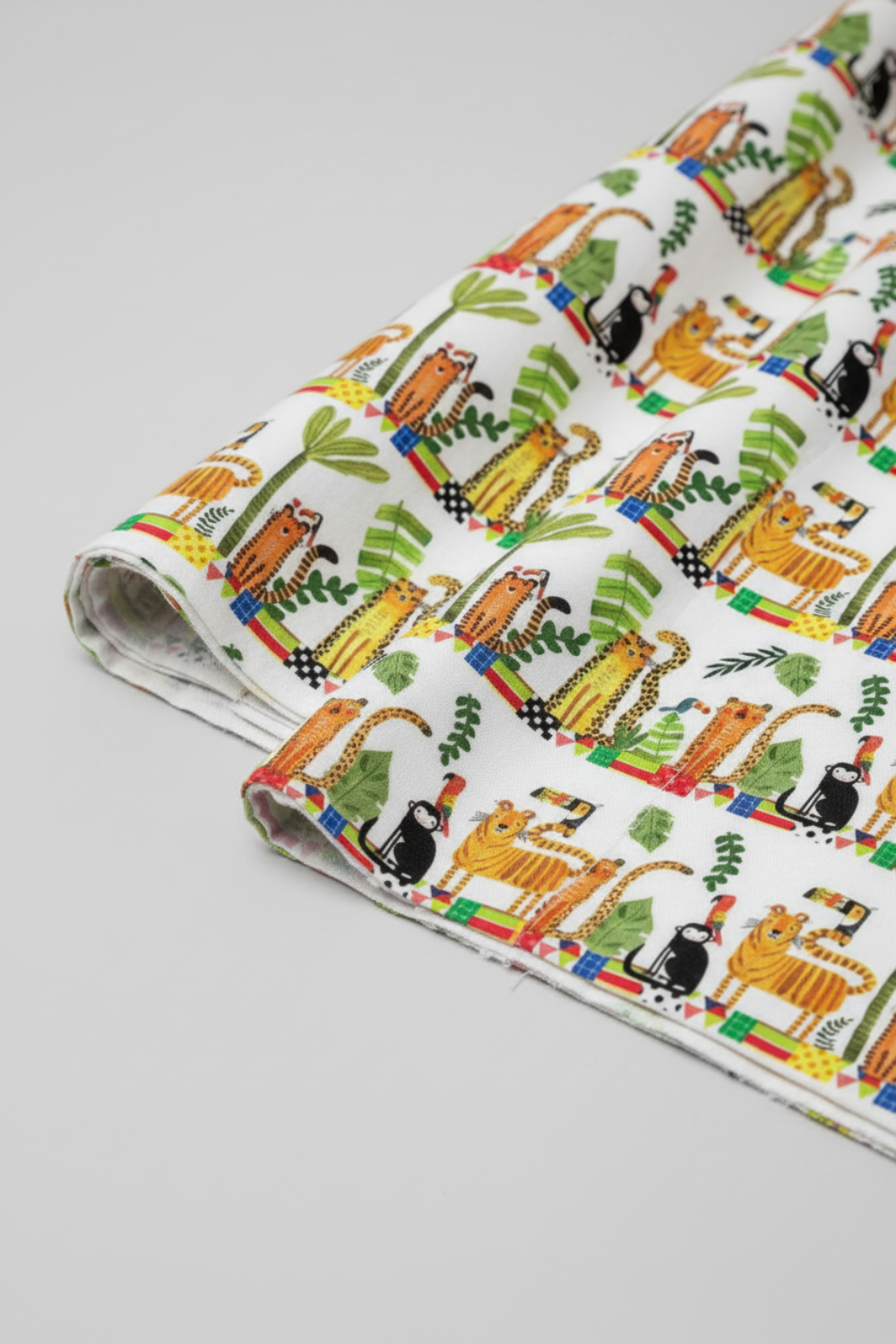Safari Fun Stripe White/Multi by Terry Runyan for Benartex – fabric rolled and folded at an angle showing the jungle animal stripe print and fabric drape, light grey background
