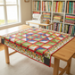 Finished Safari Fun child's quilt laid on a wooden cutting table in a bright quilting room — triangle star blocks with jungle leaves, blue, yellow, and green fabrics, red sashing — IraRobi Quilts