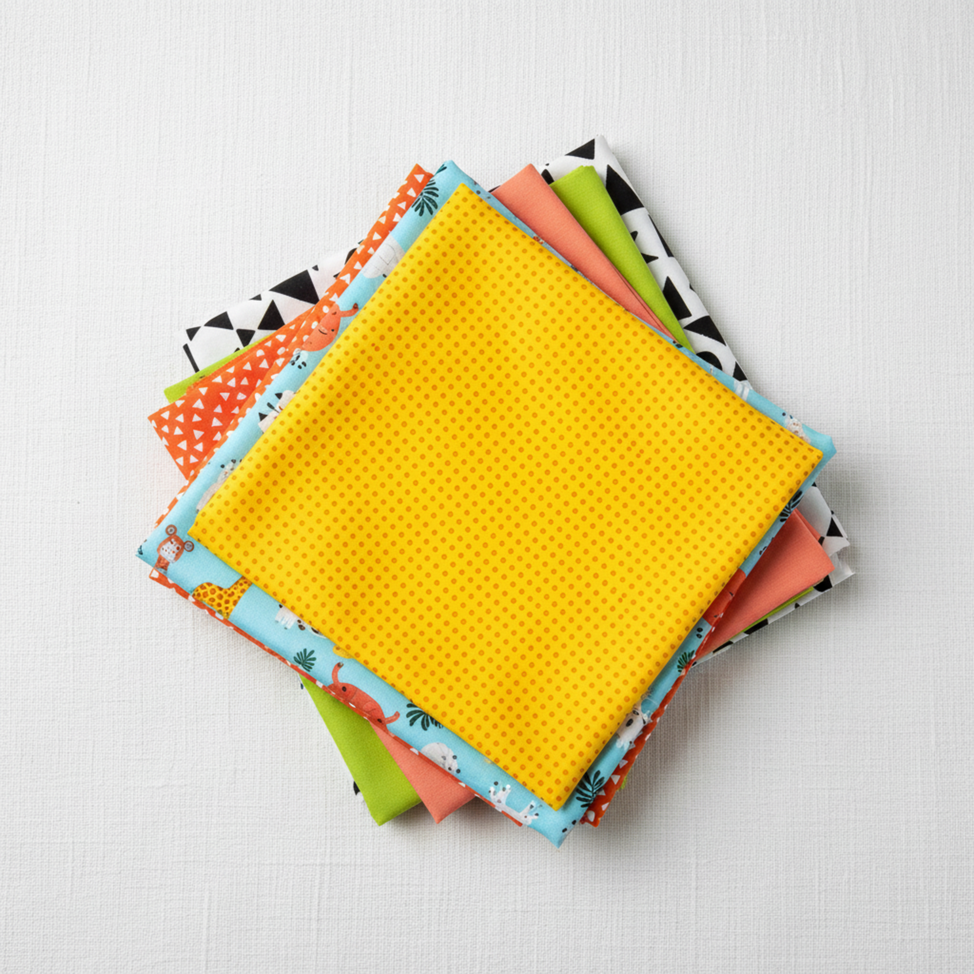 Safari Fun Random Dots Yellow/Orange by Terry Runyan for Benartex shown in a coordinating fabric stack with prints in sky blue jungle animals, orange triangles, coral sorbet, lime green, and white/black triangles. Quilt blocks shown for inspiration. Coordinating fabrics and quilt patterns are available at IraRobi Quilts.