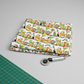 Safari Fun Stripe White/Multi quilting fabric by Terry Runyan for Benartex – neatly folded fabric with green cutting mat and rotary cutter, quilt room lifestyle shot, light grey background