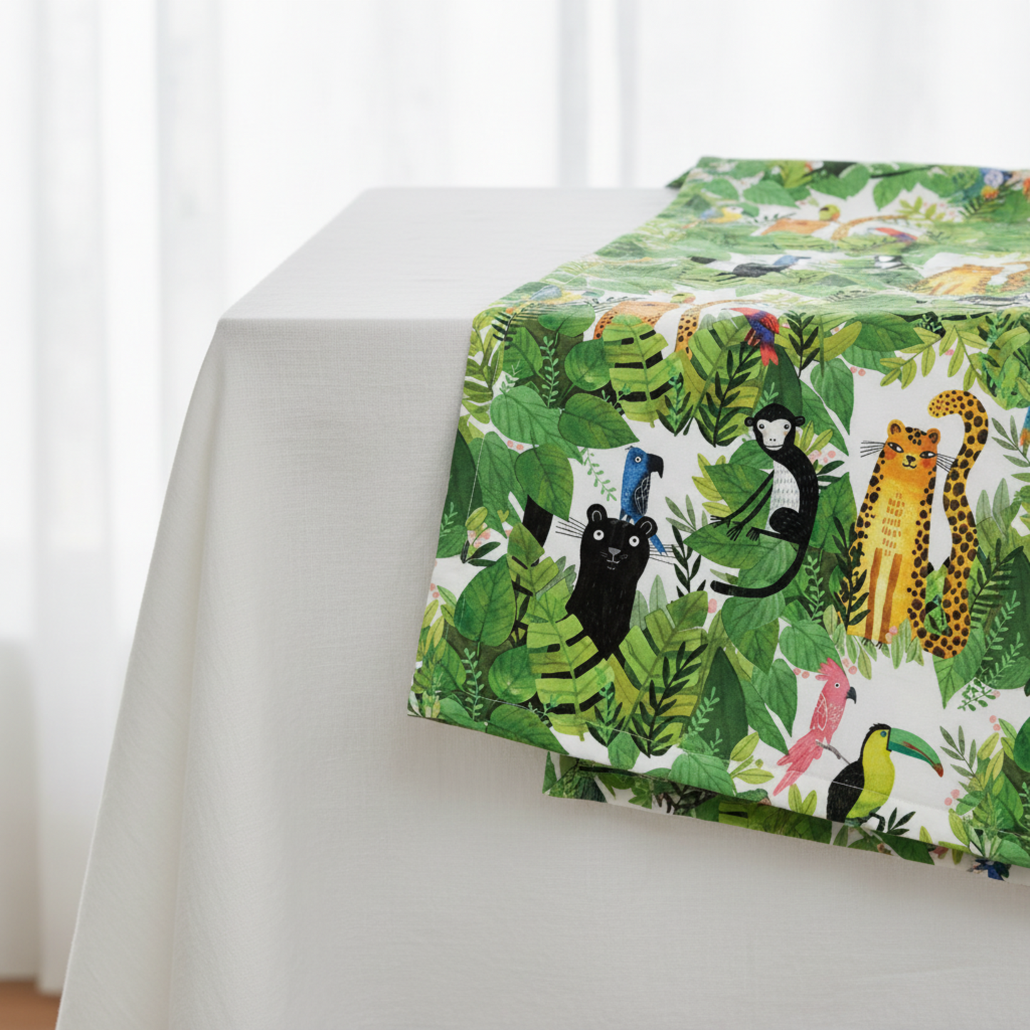 Safari Fun White/Multi quilting cotton by Terry Runyan for Benartex — large-scale watercolor jungle animals and tropical foliage on crisp white — draped softly over a white table showing fabric hand and print scale, 100% cotton. Quilt blocks shown for inspiration. Coordinating fabrics and quilt patterns are available at IraRobi Quilts.