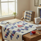 Interwoven Red Fabric by Jason Yenter for In The Beginning Fabrics as sailboat sails and red patchwork accents in a Sailing School quilt displayed on a sewing table — vivid true red crosshatch tonal blender with scarlet-to-warm-red depth, paired with navy and periwinkle scrappy plus blocks on a cream background. Quilts shown for inspiration feature the Sailing School Quilt Pattern by Joanne Kerton of Canuck Quilter Designs — available at IraRobi Quilts.