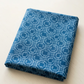 Serena Shores Coastal fabric by Robin Pickens for Moda Fabrics, neatly folded on a light tabletop with pale blue linked rings and intersecting lines on deep blue cotton.