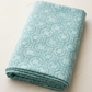 Serena Shores Mist fabric by Robin Pickens for Moda Fabrics, neatly folded on a cream tabletop with muted teal linked rings and intersecting lines on pale aqua cotton.