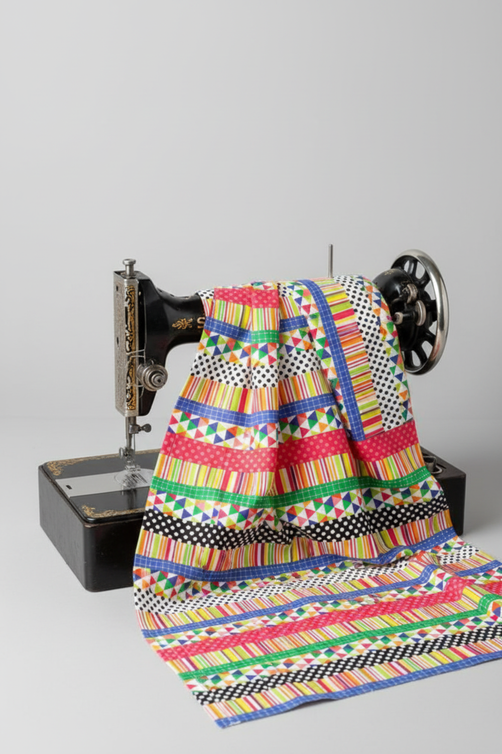 Multicolor strip print quilting cotton draped over a vintage black Singer sewing machine — Safari Fun Playful Strip Multi by Terry Runyan for Benartex — IraRobi Quilts