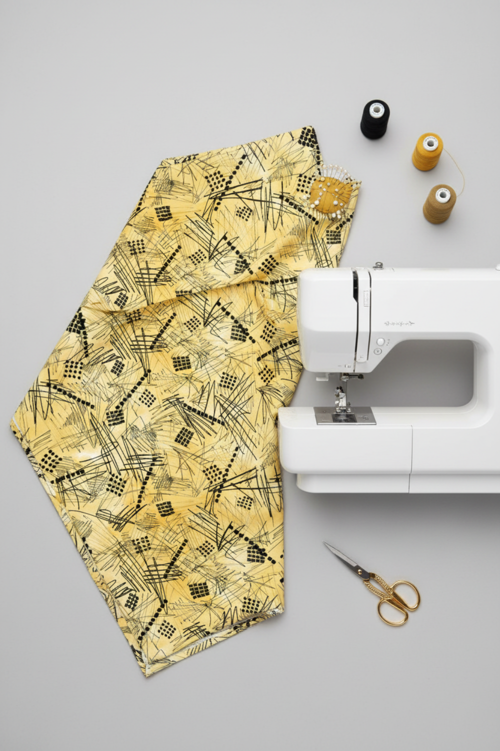 Heat Wave Bask Sun quilting cotton styled in modern sewing room with white sewing machine — golden yellow abstract print by Katie Pasquini Masopust for FreeSpirit Fabrics