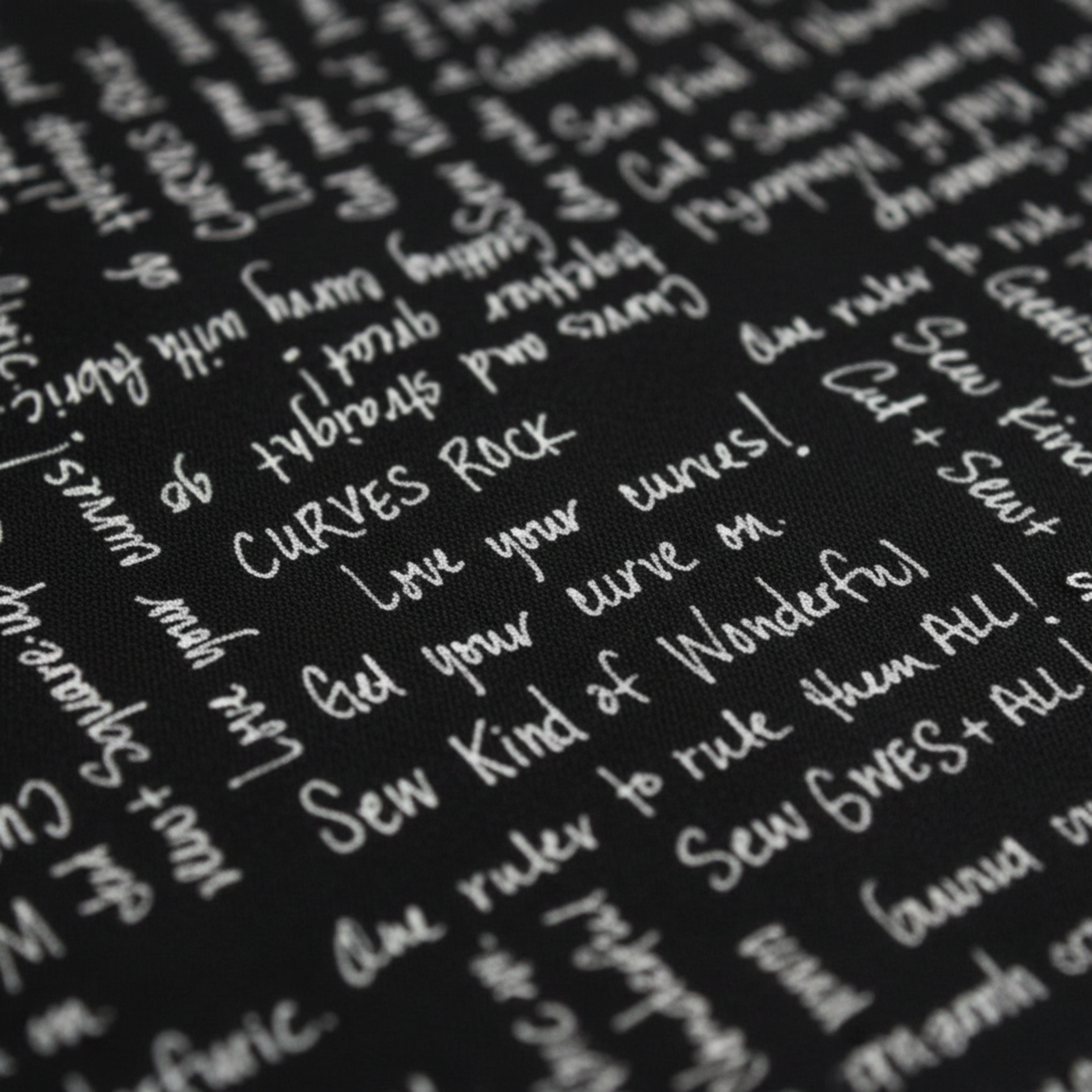 Close-up of Writing on the Wall Curves Black quilting cotton showing white handwritten script phrases: Curves Rock, Love your curves, Sew Kind of Wonderful