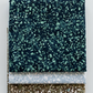 Terrazzo Smoky Teal batik fabric by Riley Blake Designs stacked above coordinating pale blue-gray and khaki speckled fabrics on a light gray background.