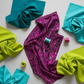 Needle Stars Chandelier Fuchsia fabric styled with Interwoven Teal, Turquoise, and Citron quilting cottons — split-complementary color palette with thread spools
