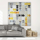 Spotted Geese flying geese quilt made with Interwoven Dark Slate as near-black geese, Slate as grey geese, Butterscotch and Pumpkin as gold and orange geese on a light background, hung above a grey sofa in a modern Scandinavian living room – Interwoven Dark Slate fabric by Jason Yenter for In The Beginning Fabrics, available at IraRobi Quilts