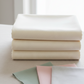 Spotted Ivory fabric by Zen Chic for Moda Fabrics folded on a linen surface with coordinating fabric cuts – soft warm ivory near-solid blender perfect for quilt backgrounds and modern quilts