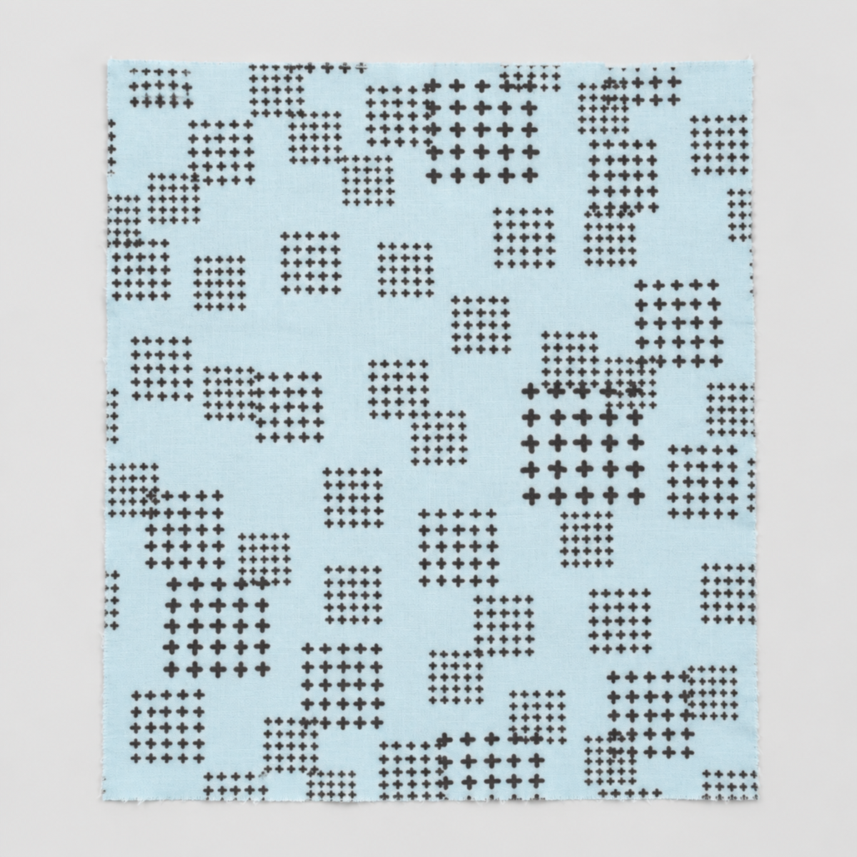 Flat swatch of Lazy Afternoon Sky Fabric by Zen Chic for Moda Fabrics on a light gray background, showing its pale blue print with black cross-shaped marks.