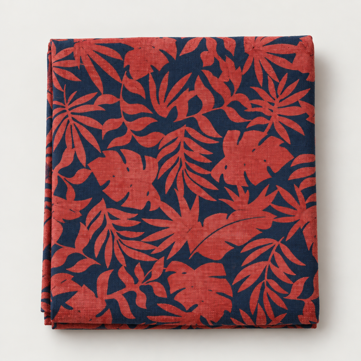 Folded Breezeway Red/Blue Textured Palms fabric displayed on a light background, showing red palm and monstera silhouettes over a deep blue ground.