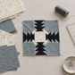 Enfold-inspired quilt block in progress on a sewing table, with Modern Background Even More Paper fabric remnants, pins, thread, and a ruler nearby. Quilts shown for inspiration feature the Enfold Quilt Pattern by Zen Chic — all available at IraRobi Quilts.