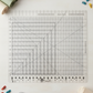 Creative Grids Stripology XL Ruler — a large clear acrylic quilting ruler with grid markings, cutting slots, and diagonal angle lines — centered on a neutral surface with fabric strips in rust, mustard, cream, and sage, a rotary cutter, fabric clips, and a thread spool arranged around the edges