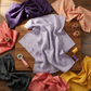 Pale lavender-periwinkle hand-dyed batik fabric styled with coordinating jewel-tone batiks in dark purple, coral, charcoal and gold in a cozy quilting sewing room – Expressions Batiks Hand-Dyes Periwinkle by Riley Blake Designs at IraRobi Quilts