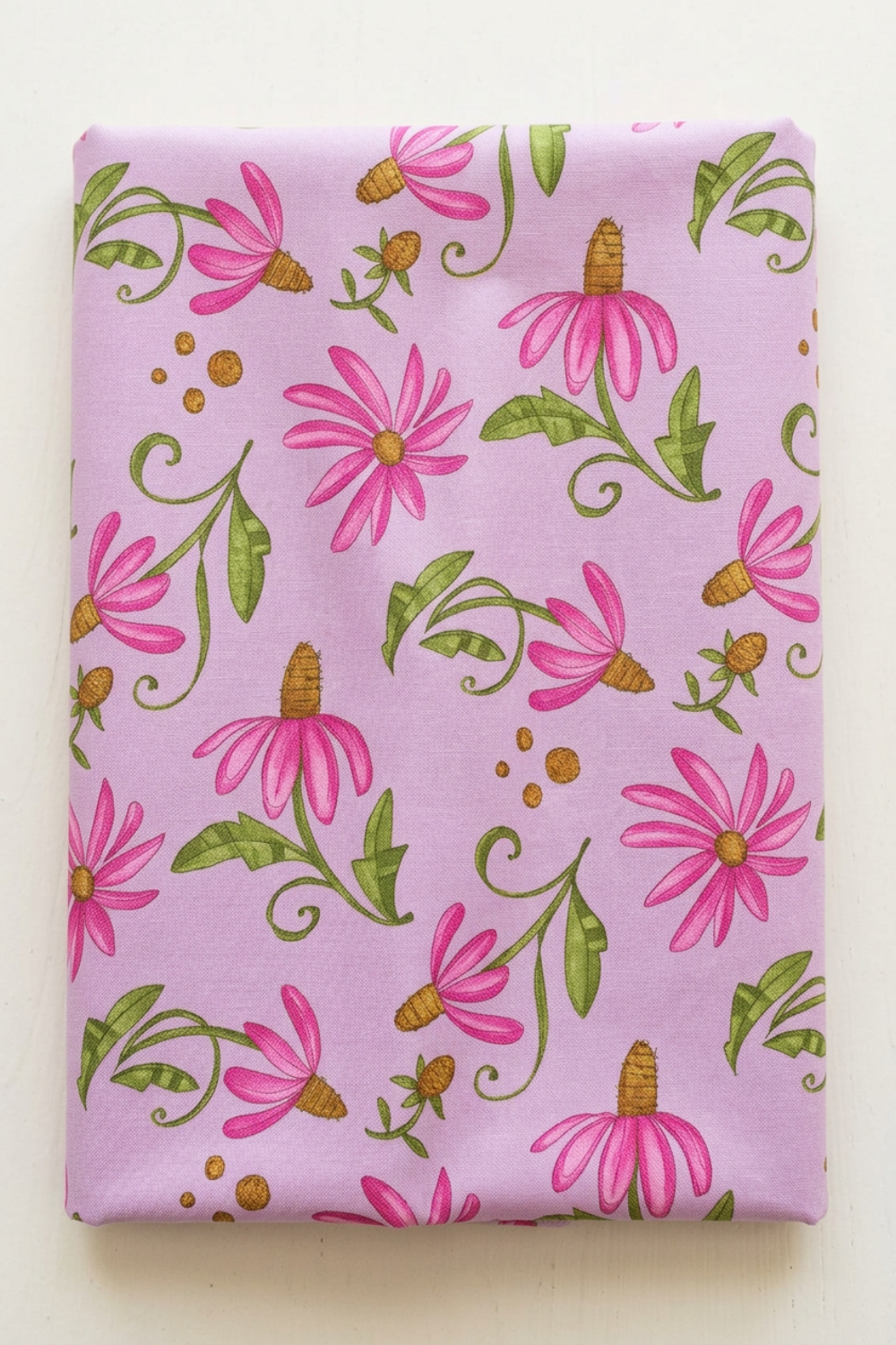Superbloom Daisyish Freesia fabric by Robin Pickens for Moda Fabrics, neatly folded on a light surface with pink flowers, golden-brown centers, and green leaves on lavender-pink cotton.
