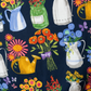 Superbloom Flea Market Vases Indigo fabric by Robin Pickens for Moda Fabrics, draped across a light surface to display colorful floral pitchers, green jars, yellow watering cans, and bouquets.