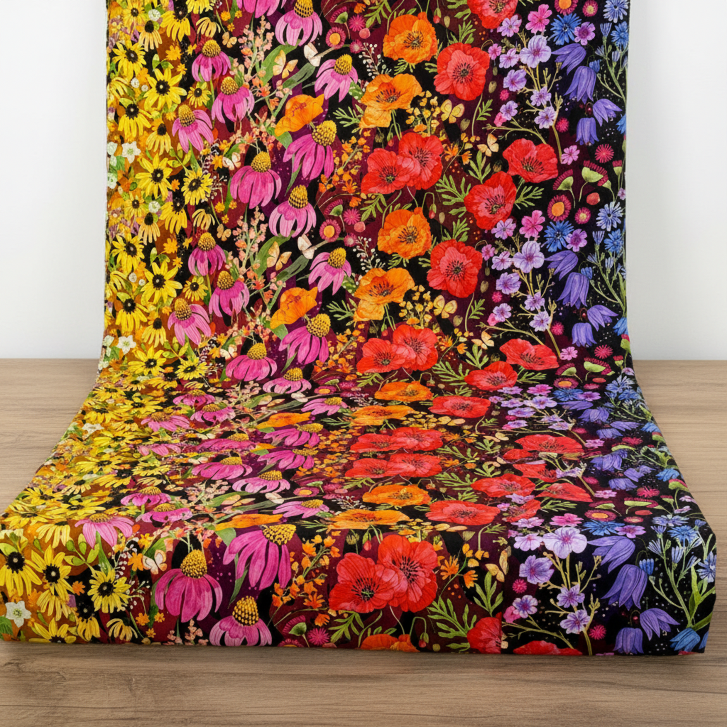 Superbloom Jewel ombré floral quilting cotton by Robin Pickens for Moda Fabrics draped over wood surface – full rainbow sweep from yellow sunflowers through pink coneflowers, red poppies, and purple bluebells – available at IraRobi Quilts